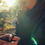 Brittany is smiling, holding and staring at her phone. She's wearing a coat and a scarf and standing outdoors.