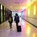 The rear view of two women walking side by side through an empty airport corridor